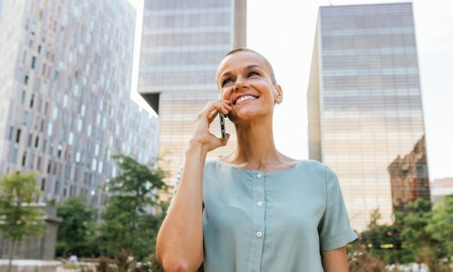 Business Woman with Buzz Cut Smiling While Attending to Phone in Business Park