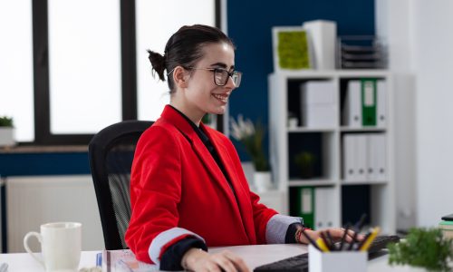 Smiling startup owner with glasses working at desk in office