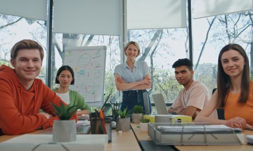 Smiling startupers looking camera modern cabinet. Five people sitting together